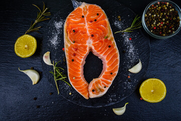 Raw salmon steak and spices on a slate board. Top view