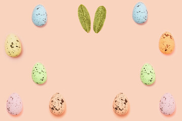 Easter eggs decoration with easter bunny ears flat lay on peach color background with copy space