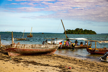 Tanzania, Zanzibar, tourists are loading on to a traditional dhow sailing boat on the coast of Zanzibar