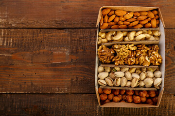 Assorted nuts in packaging on a brown wooden table. Copy space