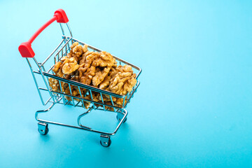 Food cart filled with peeled walnuts on a blue background. Copy space.