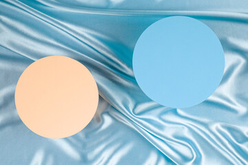 Two round platform podiums on light blue silk satin background. Blank minimal cylinder form mock up background for cosmetic product presentation