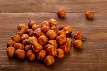 Hazelnuts are scattered on a dark wooden table.