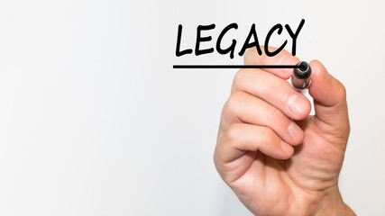 the hand writes text LEGACY with a marker on a white background. business concept