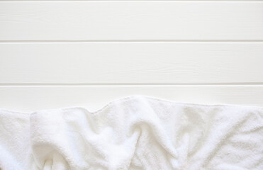 A white terry towel lies on a white wooden table. Cleanliness and hygiene. Bathroom. Sun lounger by the pool, spa treatments.