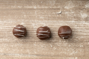 detail of three dark chocolate balls with white decoration, elegant gourmet dessert style in studio