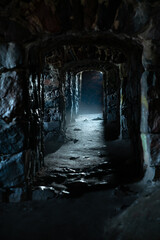 A dark, damp, cold dungeon corridor with stone walls all along the hallway