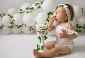 A child with an appetite eats a birthday cake for his first birthday. Festive decor made of...