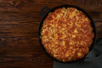 Macaroni with cheese in a pan on an old wooden table.