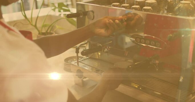 Animation of lens flare and sunlight with hands of barista preparing coffee using machine