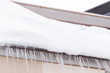 A closeup shot of snow and icicles on a roof