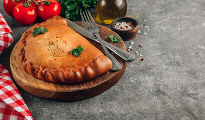 Italian food, closed pizza calzone with cheese, gray stone background. Selective focus