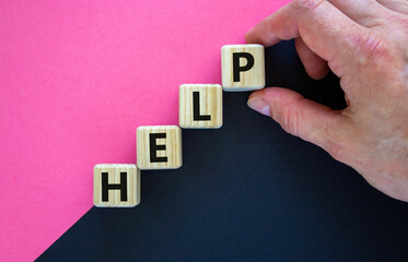 Support and help symbol. Wooden cubes with the word 'help'. Businessman hand. Business, psychology, support and help concept. Beautiful purple and black background, copy space.