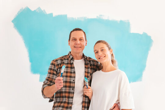 Couple doing repairs and painting walls in blue. Family during apartment renovation concept.