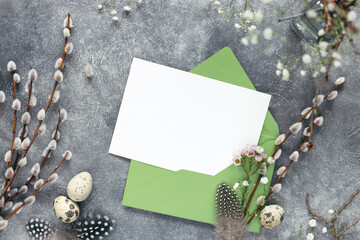 Empty card on Easter decorated table with willow twigs. Mockup, top view.