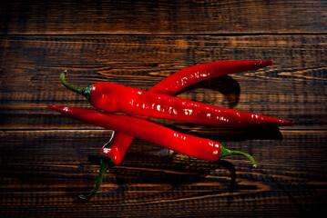 Red pepper on a brown wooden board. Vegetables on a black background. Contrasting dramatic light as...