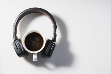 Headphones and coffee cup on white background