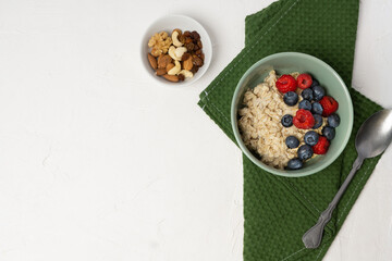 Oatmeal with fresh berry fruits. Oat porridge in a bowl with spoon and blueberries and raspberries.
