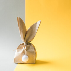 Easter bunny paper gift egg wrapping DIY idea on colorful background. Minimal easter concept, flat...