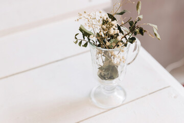 A small bouquet of dried wildflowers in a transparent glass beaker.