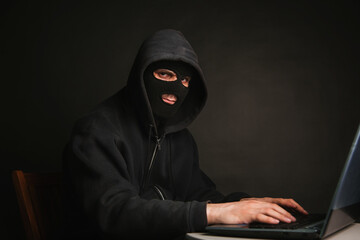 A dangerous masked hacker with a hood infiltrates data servers and infects their systems with...