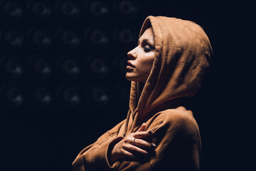 Studio portrait of a girl in a hoodie on a dark background