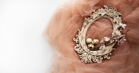 Old oval carved frame with spring flowers and eggs on pastel background. Spring flowers composition with copy space.