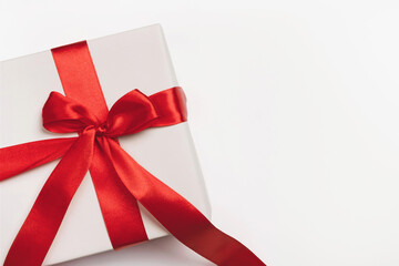 White gift box with red ribbon bow on light background. Christmas, new year, birthday, anniversary or sale background. Top view, flat lay, copy space, template for design