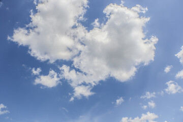 Obraz premium Two big fluffy clouds in blue sky fading lighter on right side.