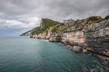 Beautiful seascape. Stormy sea on a windy day: blue waves breaks on the stone shore of Porto Venere...