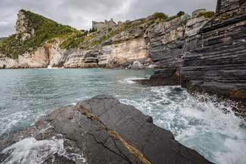Beautiful seascape. Stormy sea on a windy day: blue waves breaks on the stone shore of Porto Venere...