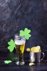 Patrick's day, beer, chips in an iron mug, shamrock on a dark background, party, congratulations, postcard