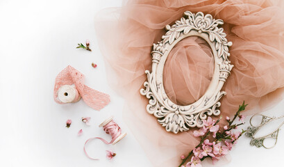 Vintage spring background with shabby photo frame, cherry blossom branch, fabric, french lace and satin ribbon. Pastel colors. Top view with copy space.