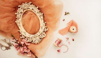 Vintage spring background with shabby photo frame, cherry blossom branch, fabric, french lace and satin ribbon. Pastel colors. Top view with copy space.