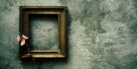 Vintage old wooden frame with spring flowers and leaves on dark rustic wooden background. Spring flowers composition with copy space.