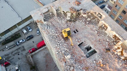 Building demolition in the city center. The excavator is on the top floor of the apartment building.