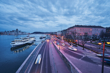 Danube River at blue hour twilight in city of Budapest, Hungary, Cruise and dinner boat near riverside promenade.