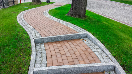 Stairs with red gray cobblestones, among the grass
