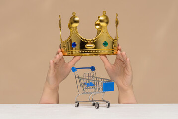 Empty shopping cart and golden crown above on a light background.