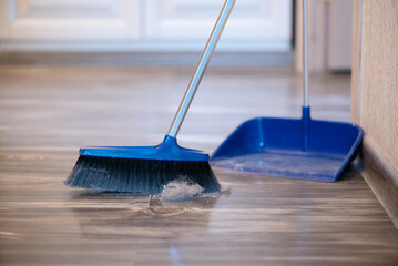 Broom brush and dustpan on the floor. Home cleaning.