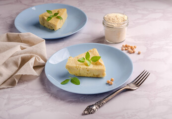 Slice of veggie pea flour omelet and basil herbs on light gray background