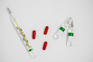 Medical drugs and thermometer close up on white background