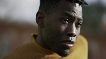 Black African man working in front of laptop sitting on floor outside