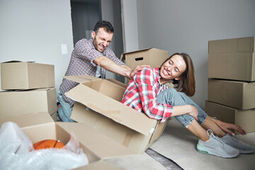 Man forcing a smiling lady out of the cardboard box