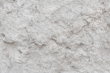 Rough, uneven texture stone of a gray concrete wall close up