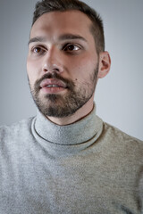 Fototapeta premium Portrait of a young brown-haired man with a short beard and a gray turtleneck sweater 