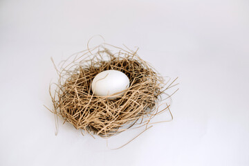 White egg in a nest and two white eggs on a white background close up