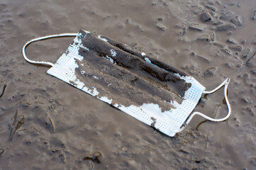 discarded medical mask in the mud