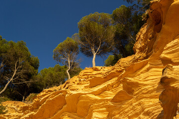 A sedimentary sandstone formation with vibrating yellow and orange colors  on a warm sunny day in the isalnd of Mallorca Spain