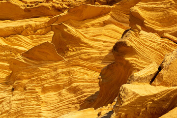 A sedimentary sandstone formation with vibrating yellow and orange colors  on a warm sunny day in the isalnd of Mallorca Spain
